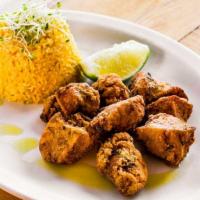 Chicharrones De Pollo · Crispy chicken chunks served with yellow rice and black beans.