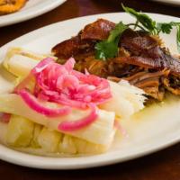 Pernil · Slow-roasted marinated pork shoulder, served with boiled yuca and pickled red onions.