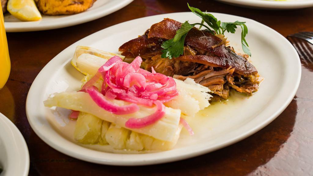 Pernil · Slow-roasted marinated pork shoulder, served with boiled yuca and pickled red onions.