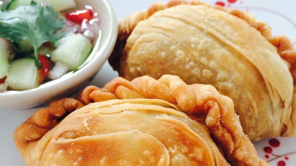 Curry Puffs · Flaky thai pastries filled with potato, onion and chicken in a thai curry seasoning. Served with a cucumber vinaigrette dipping sauce.