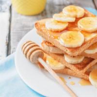 Banana French Toast Deluxe · Fresh french toast with bananas topped with syrup and choice of meat on side.