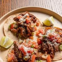 Carne Asada Tacos · Chile rubbed skirt steak, chipotle caramelized onions, and cotija cheese.