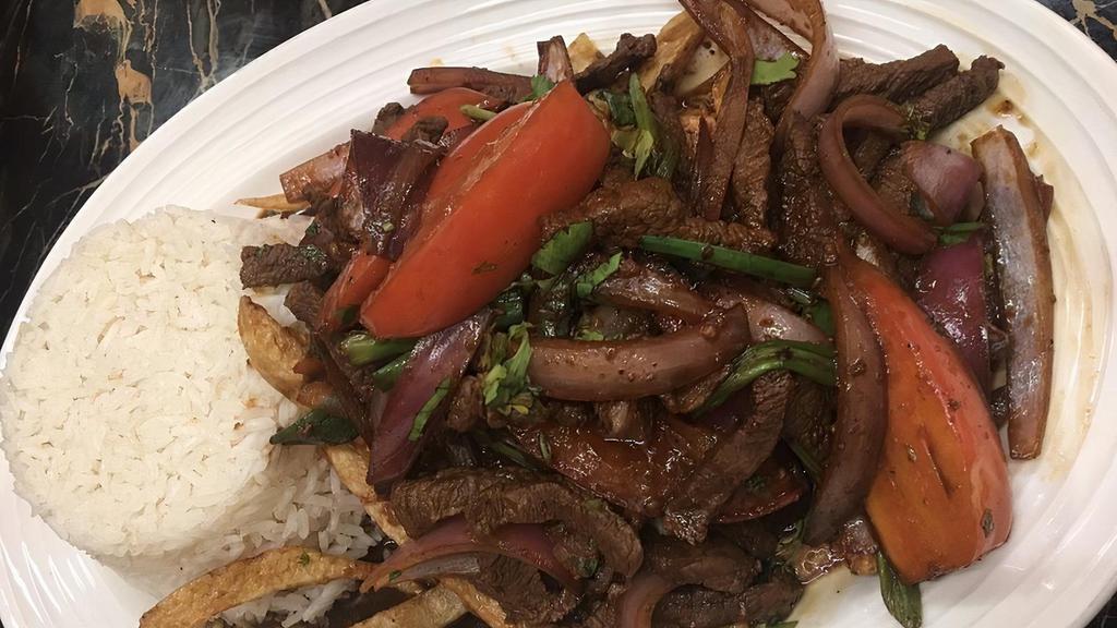 Lomo Saltado · Tender beef sautéed with onions and tomatoes in a soy sauce served with French fries and white rice.