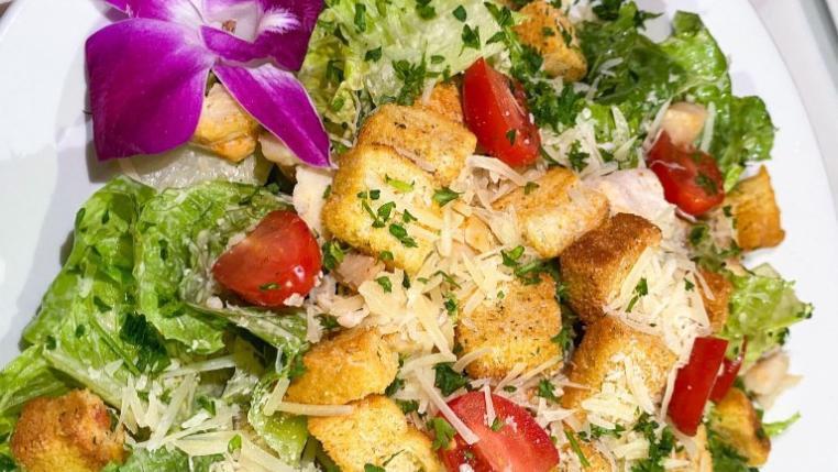 Caesar Salad · Chopped greens tossed with Caesar dressing, topped with grilled chicken and baby tomatoes.