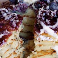 Berry Sour Bliss Pancakes · Buttermilks baked with blueberries and coconut, topped with our warm blueberry compote and d...