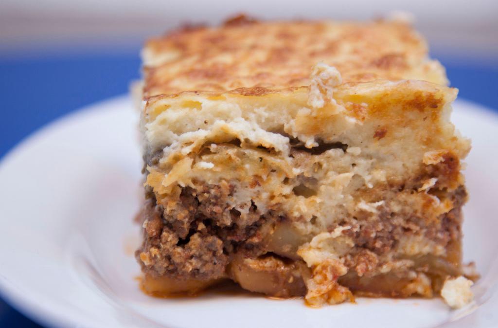 Moussakas · Traditional Greek casserole with béchamel sauce, ground beef, eggplant, and potatoes.