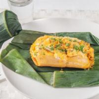 Bollo De Pescado · Creamy green plantains grated then packed with fish and peanut sauce inside a banana leaf.