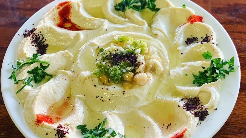 Hummus · Chickpeas mashed with tahini, garlic, lemon juice and olive oil. Served with fresh baked pita, olives and pickles.