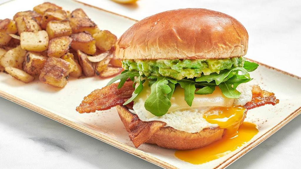 Elevated Egg Sandwich · Fresh, over easy cage-free egg with bacon, Gruyere cheese, fresh smashed avocado, mayo, and lemon-dressed arugula on a brioche bun. Served with fresh seasoned potatoes.. *Please note: Our potatoes are cooked with onions. We are unable to accommodate onion removal requests for dishes containing potatoes.