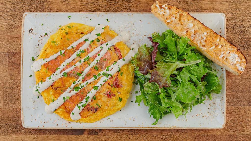 Smoked Salmon & Roasted Vegetable Frittata · A classic frittata with Wild Alaska Smoked Sockeye Salmon*, house-roasted shallots and tomatoes topped with Parmesan cheese, a chive cream drizzle and fresh herbs. Served with ciabatta toast and lemon-dressed organic mixed greens.