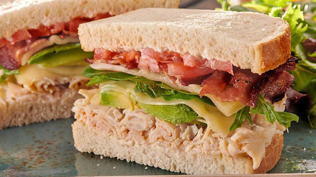 Monterey Club Sandwich · Turkey, bacon, avocado, organic mixed greens, tomato, Monterey Jack, and mayo on sourdough. Served with lemon-dressed organic mixed greens or a bowl of tomato basil soup.