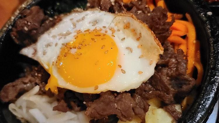 Bulgogi Dolsot · Beef rib-eye hot stone rice bowl topped with sauteed vegetables. Served with kimchi and spicy cucumber.