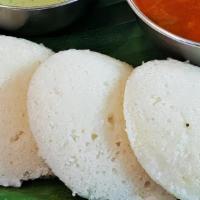 Idli (2) · Steamed rice cake served with sides of sambar & chutneys.