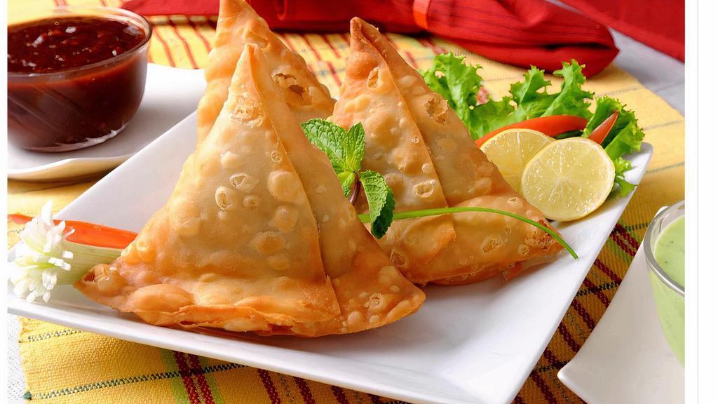 Samosa · Crispy, deep-fried triangular pastry, filled with potatoes and green peas, and flavored with fresh herbs and spices.