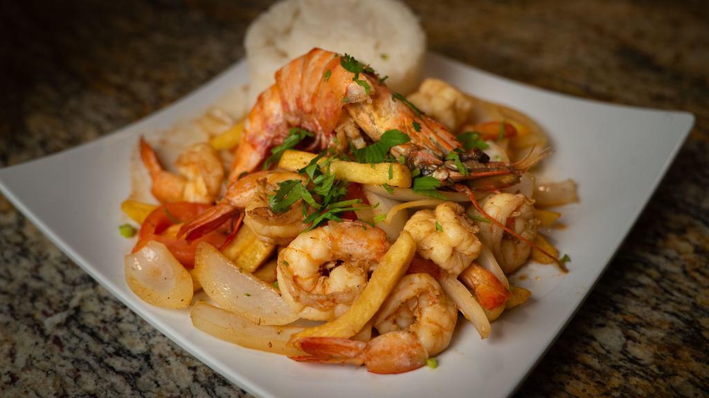 Saltado De Camarones · Traditional Peruvian stir-fry, with shrimps, red onions, and tomatoes. Served with French fries, white rice and topped with cilantro.