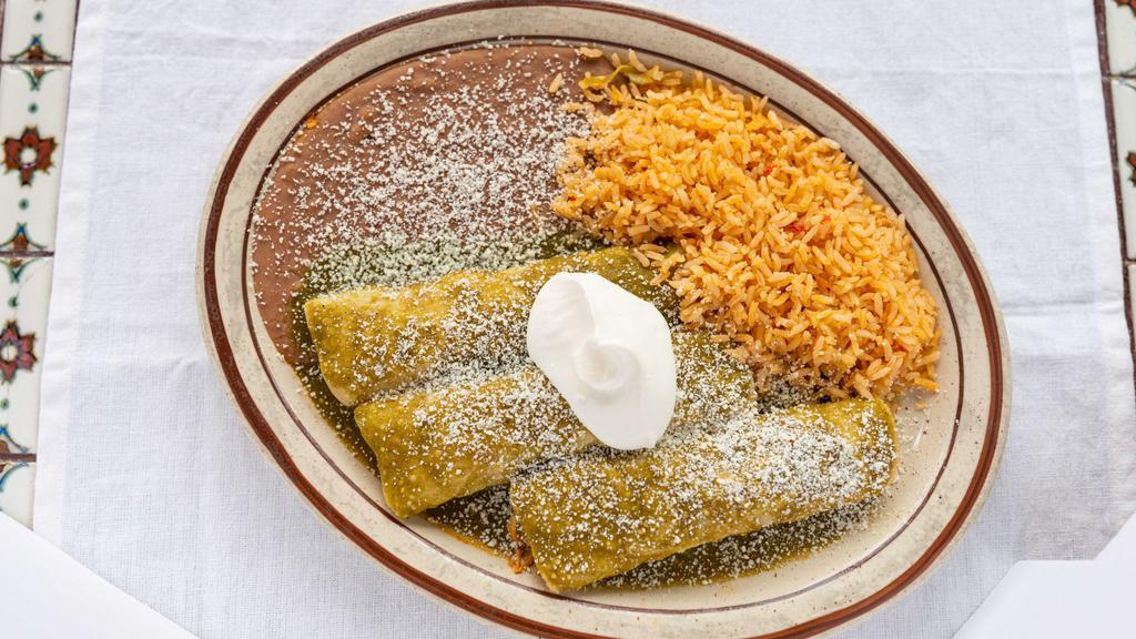 Lunch Enchiladas Suizas · Two chicken enchiladas topped with cheese sauce, green salsa and cilantro. Served with rice and beans.