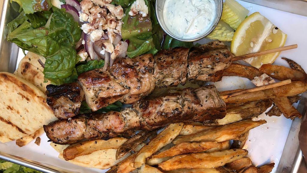 Souvlaki Plate · Two skewers of marinated grilled chicken or pork, salad, feta, hand cut oregano fries, and tzatziki.