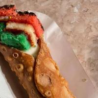 Rainbow Cookie Cannoli · A large cannoli topped with a rainbow cookie.