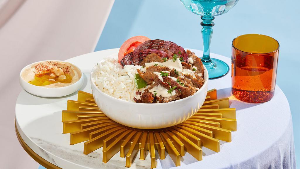 Lamb Shawarma Bowl · Juicy lamb over rice with hummus, tomatoes, grilled onions, and drizzled with your choice of sauce.