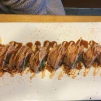 Nom Nom Roll · Spicy. Top: Torched salmon, tempura flakes and chef’s spicy sauce. Inside: Scallops, scallio...