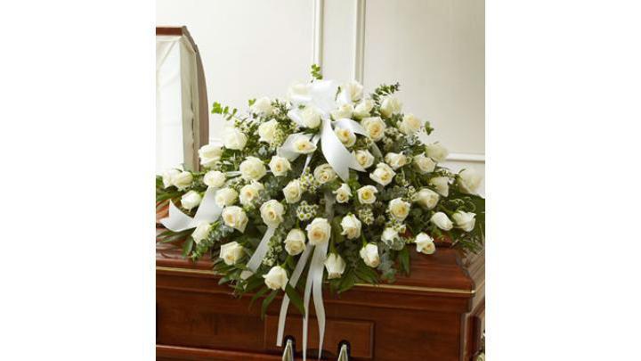Cherished Memories White Rose Half Casket Cover · Every moment spent with your loved one is a memory you want to hold onto forever. Commemorate their life, and all the feelings you have for them, with this beautiful white casket cover, crafted by our expert florists with long stem white roses, for a fitting final tribute.