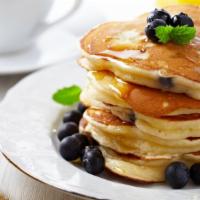 Golden Pancakes With Fresh Blueberries · Fluffy golden pancakes topped with fresh blueberries and served with a side of syrup and but...