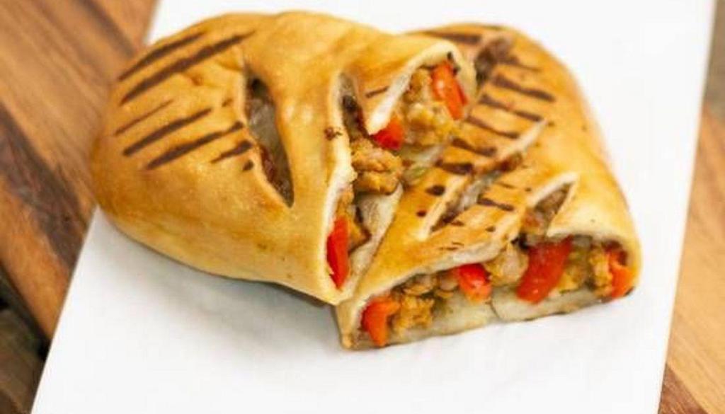 Sausage & Roasted Pepper Calzone · Crispy pizza dough filled with sweet sausage, roasted peppers, caramelized onions, and mozzarella.