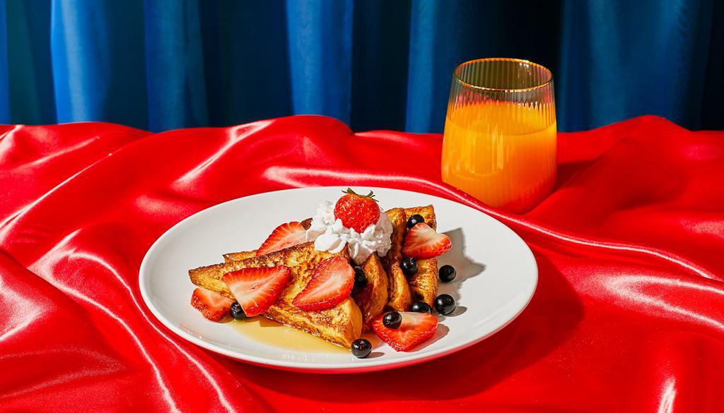 Berry French Toast · Four slices of thick, egg-washed cinnamon bread topped with fresh blueberries and strawberries, and served with maple syrup and powdered sugar.