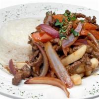 Lomo Saltado De Carne · Steak Sautéed with Onions, Tomatoes, and Soy Sauce Over a Bed of French Fries, Served With a...