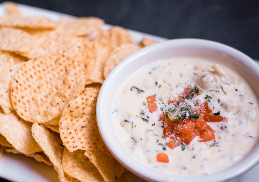 Spinach Artichoke Dip · Our made-from-scratch, creamy dip of artichoke hearts, spinach and Italian cheeses, garnished with diced tomatoes. Served with tortilla chips.