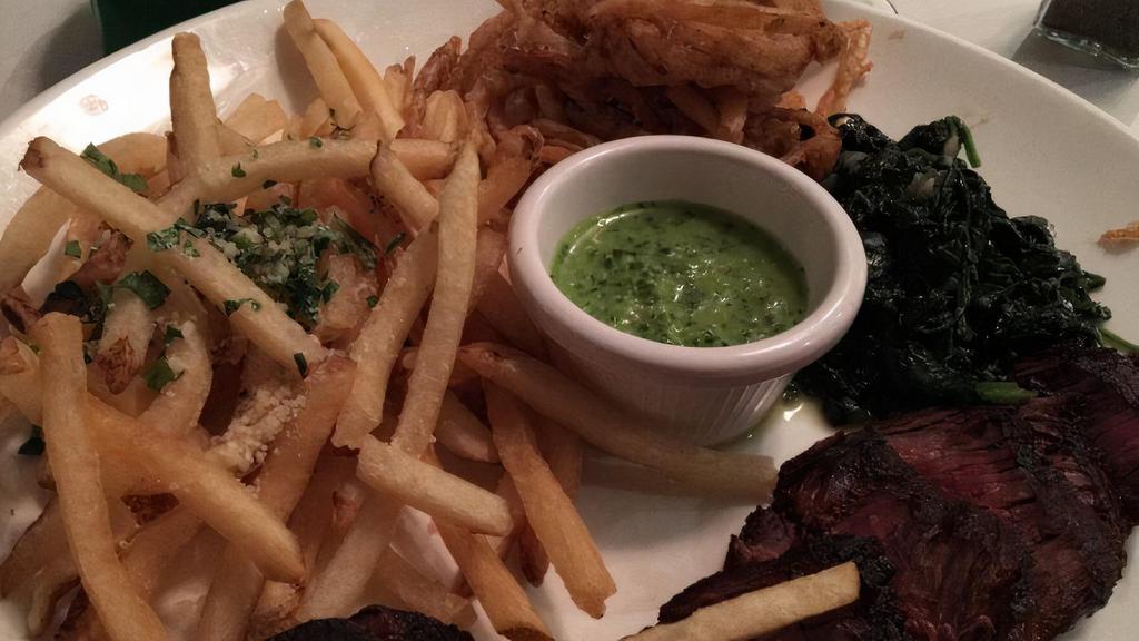 Grilled Hangar Steak Chimichurri · Served with truffle parmesan fries, fried onion strings, and sautéed spinach with chimichurri sauce.