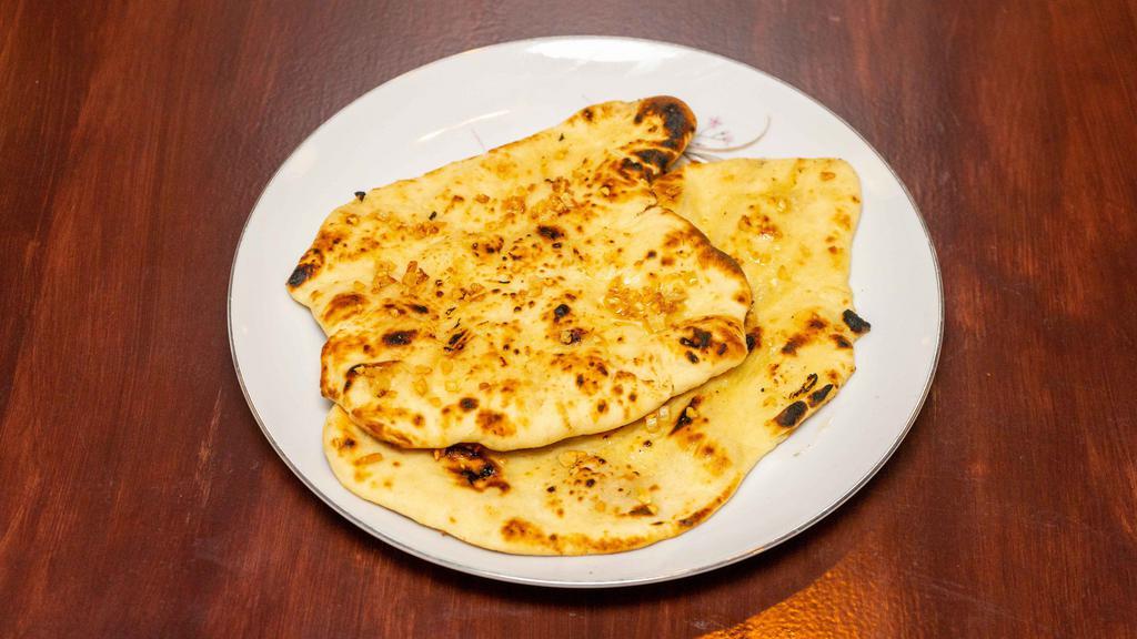 Garlic Naan · Pillowy soft naan bread glazed with garlic butter; served with a side of curry.