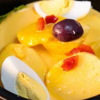 Papa A La Huancaina · Sliced baked potatoes topped with yellow Peruvian cheese cream sauce.