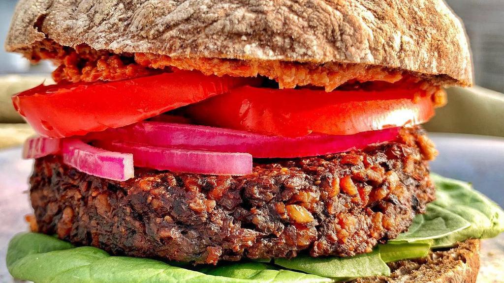 Beety Burger · Beet and walnut meat burger with baby spinach and pickled onions; served on a grainless ciabatta roll. Order it as a bowl to enjoy the burger served over kale and quinoa massaged with herb oil. Choice of sauce: spicy aioli, muhammara, almond cilantro pesto, or grainy mustard.