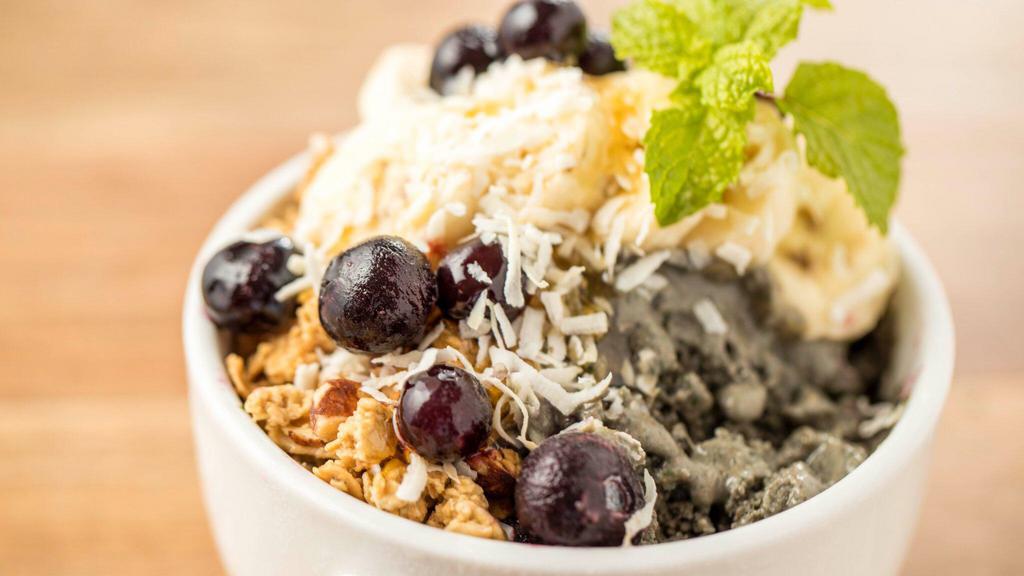 Super Green Açaí Bowl · Organic acai with organic kale, banana, coconut milk, almond butter, and almond milk topped with granola, banana, blueberries, honey, coconut flakes, and mint.