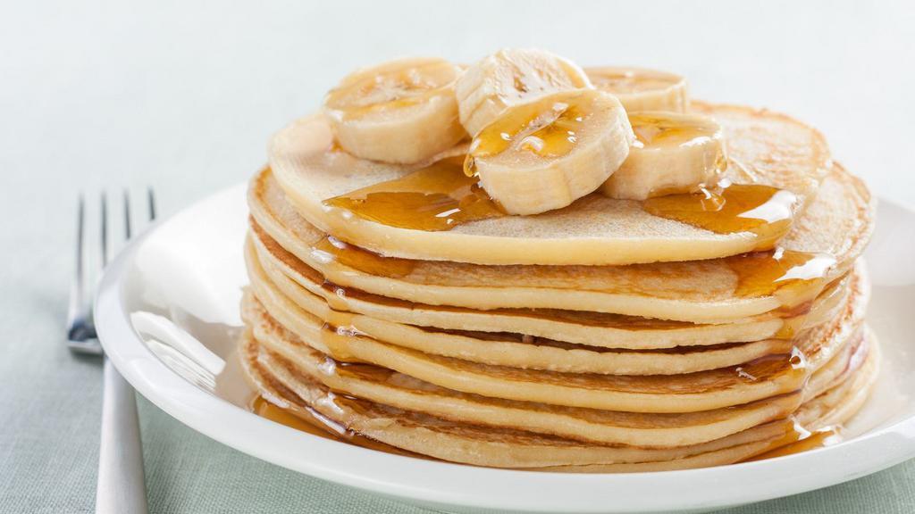 Banana Pancakes · Buttery, fluffy pancakes marbled and topped with banana and served with real butter and syrup.