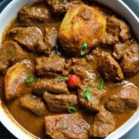 Goat Kadahi · Slow-cooked goat married with traditional herbs and spices in a traditional Indian pan.