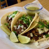 Angus Steak Tacos · 3 Flank steak tacos served with chopped white onions, cilantro, lime wedges, and salsa verde...