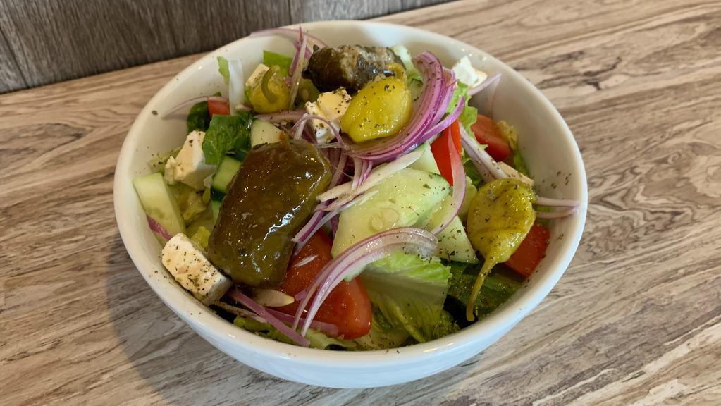 Greek Salad · Lettuce, tomatoes, cucumbers, stuffed grape leaves, red onions, pepperoncini, feta, and kalamata olives.
