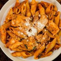 The Baked Penne Arrabbiata · Chili oil, mozzarella cheese, parmesan cheese, basil, and spicy tomato sauce sitting on a be...