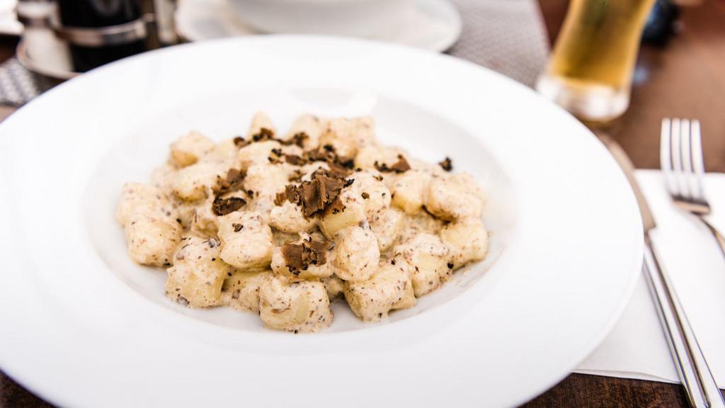 The Truffle Gnocchi · Parmesan cheese, basil, truffle paste, and fresh alfredo sauce sitting on a bed of gnocchi.