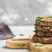 Black Bean Quinoa Burger · Vegan and gluten-free.  Served over mixed greens, topped with hummus and tomato.