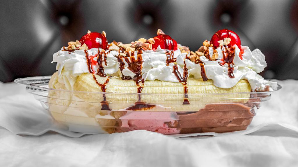 Banana Split · Banana sliced in half topped with 3 scoops of ice cream, chopped peanuts, whip cream, chocolate drizzle and a maraschino cherry.