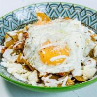 Chilaquiles · Fried tortilla chips cooked in salsa verde, topped with queso fresco, crema fresca and sunny...