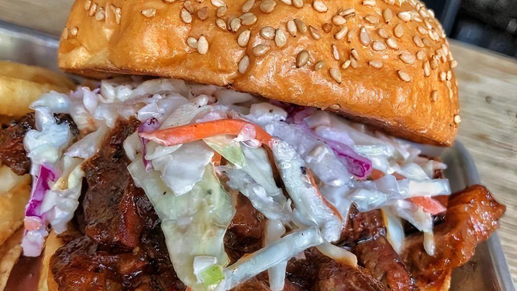 Sliced Brisket Sandwich · chopped brisket in sauce topped with cole slaw on a toasted sesame brioche bun