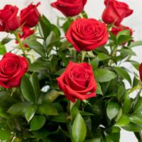 Dozen Roses · A dozen roses arranged in a clear glass vase with beautiful foliage to complement.  Rose col...