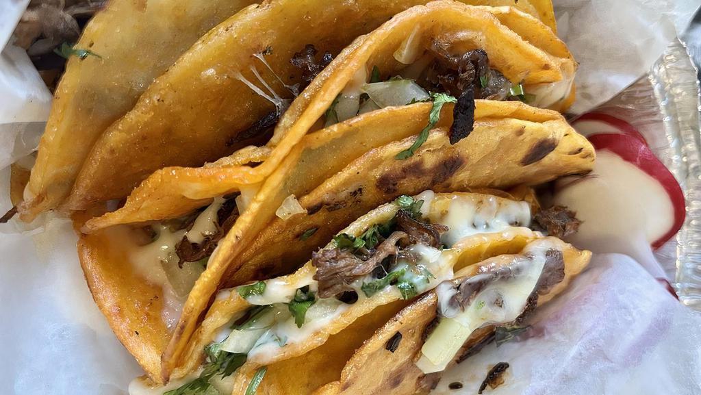 Birria Tacos · Shredded beef tacos filled with cheese cilantro and onions.