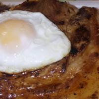 Chuleta A Lo Pobre · Grilled Pork Chop topped with 2 Fried Eggs, served over French Fries, White rice & Sweet Pla...