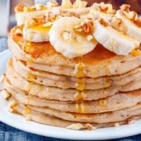 Banana Pancakes · A stack of 3 fluffy pancakes topped with locally grown sliced bananas then dusted with powde...