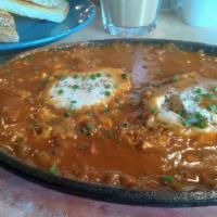 Shakshuka · Poached eggs inside an aromatic tomato sauce. Served with grilled garlic sourdough and olives
